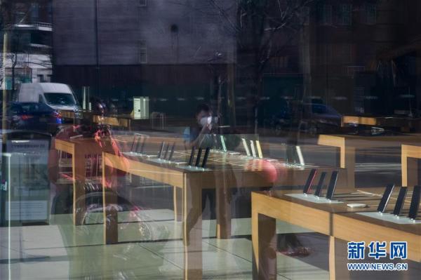 3月27日,在美国纽约,一名戴口罩行人的影子映在一家停业的苹果商店