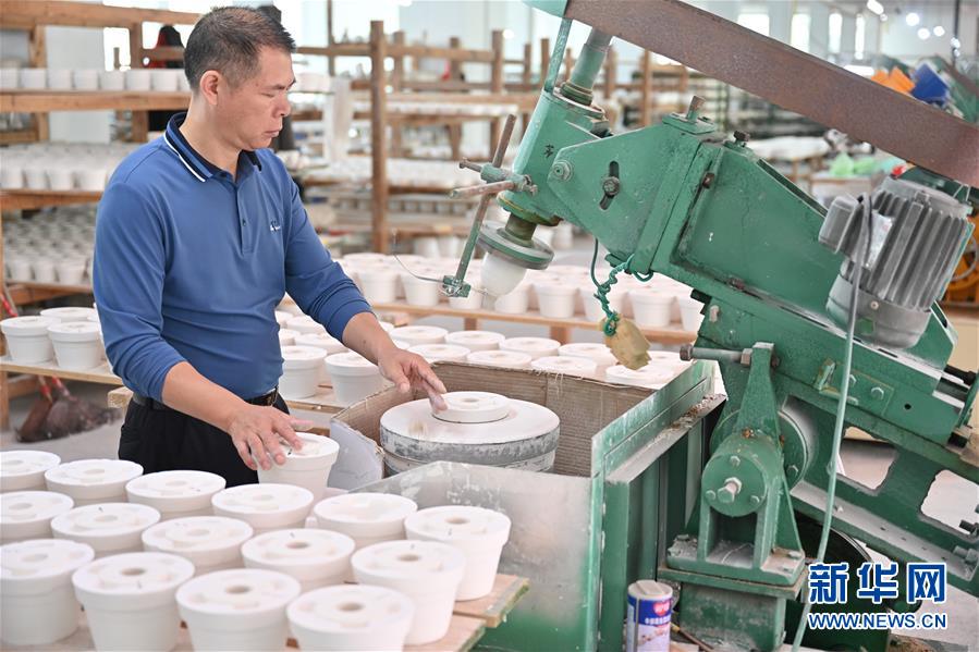 10月21日,在福建省泉州市德化县顺美陶瓷厂,工人操作机器制作陶瓷产品