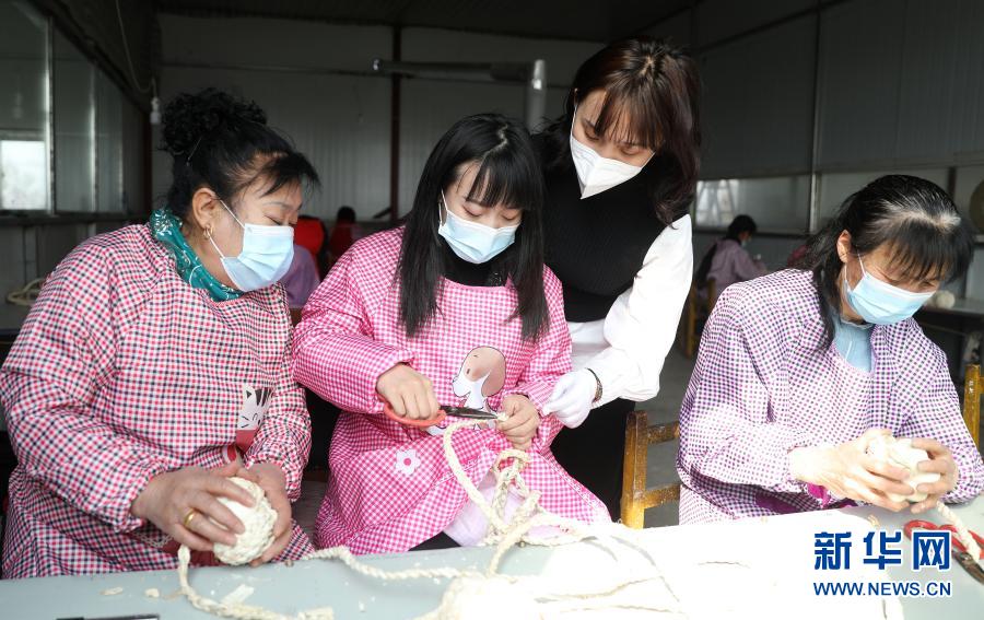 3月4日,闫佳欣(右二)在车间内指导妇女们制作手工艺品.