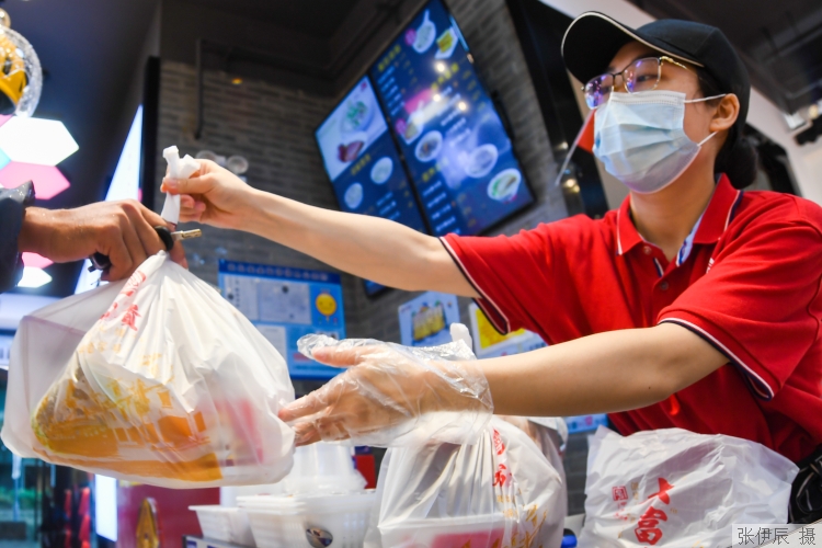 临平路瑞虹坊内的大富贵店员正将早餐打包递给外卖小哥.