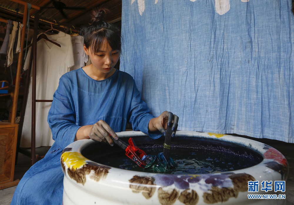 6月30日,陈燃正在将扎成花的布料放入染缸浸染