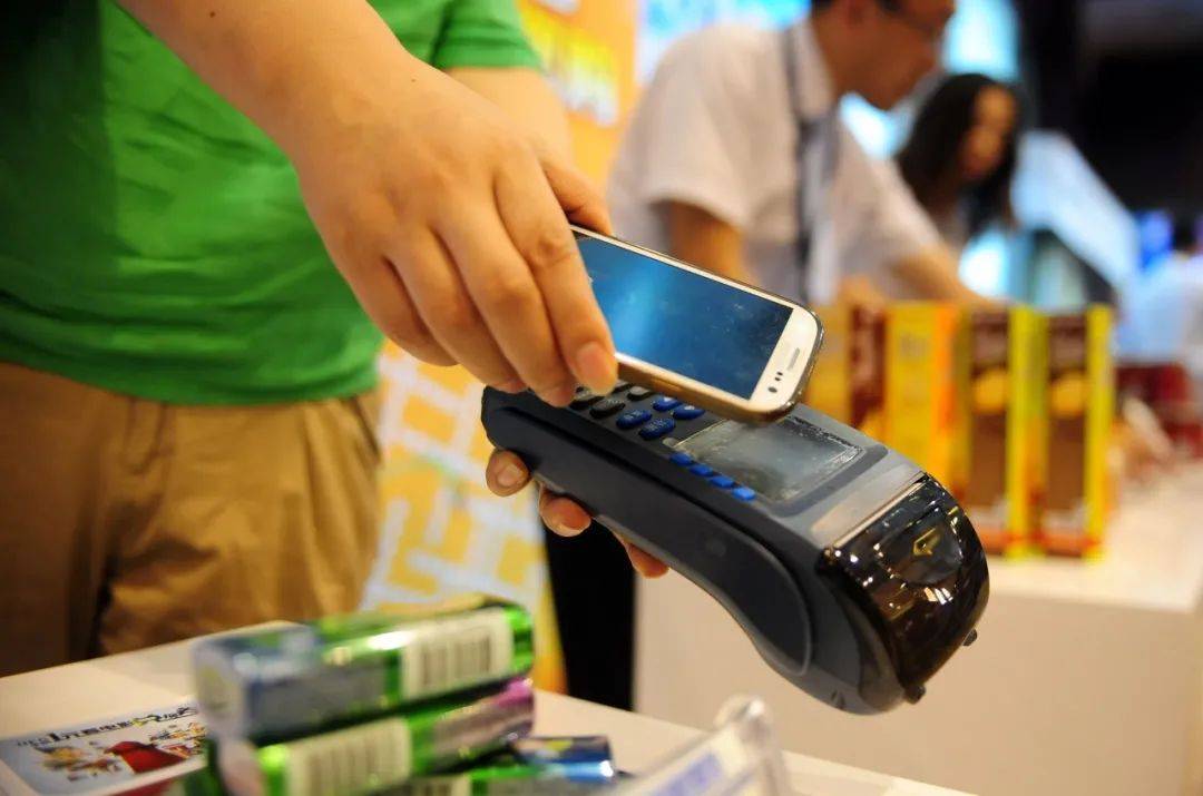 图为2013年8月20日一位工作人员演示用NFC手机支付功能进行刷卡消费。新华社发