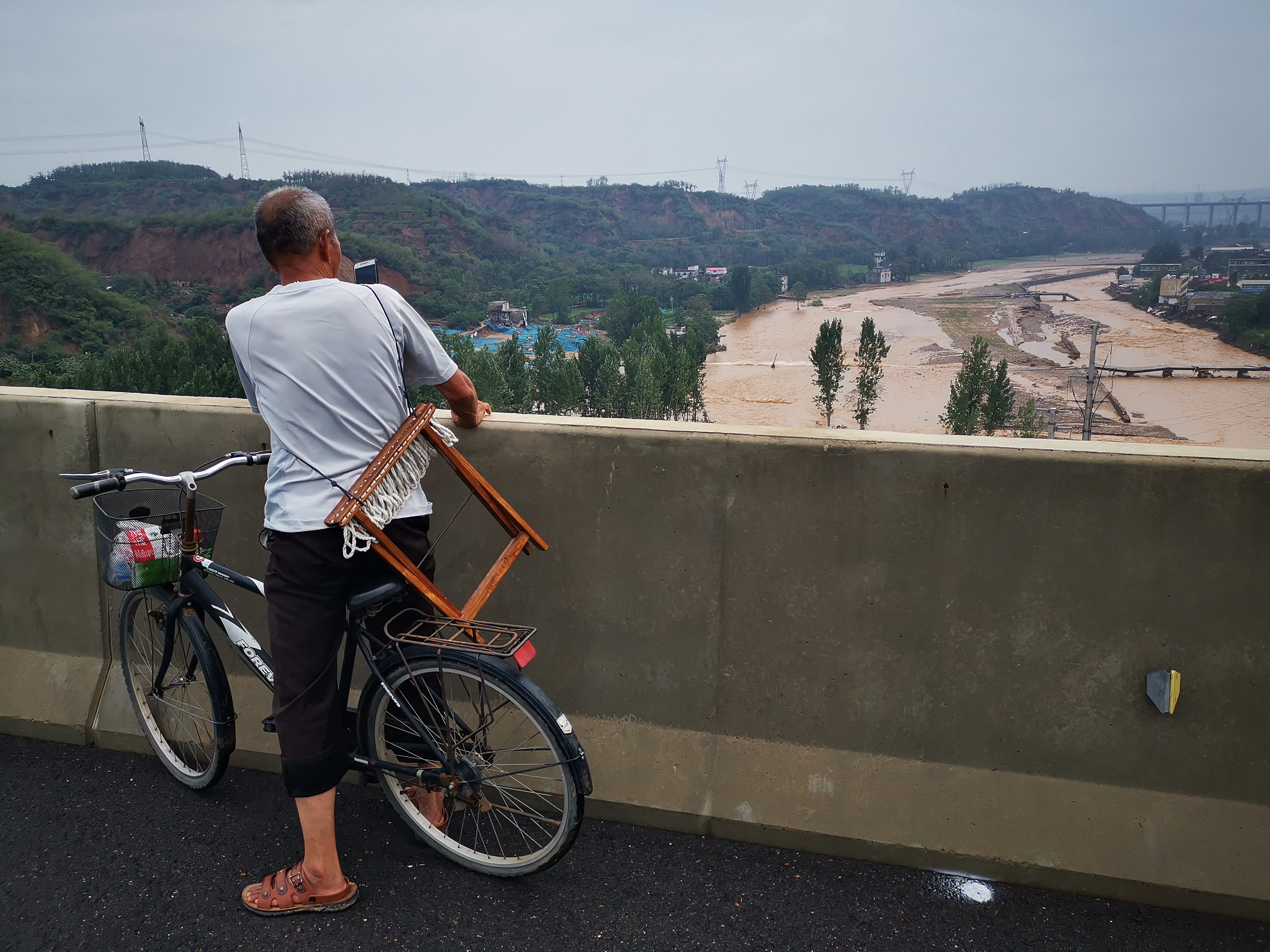 22日早晨7点20分左右,一位大爷在桥上用手机拍摄汜水河.