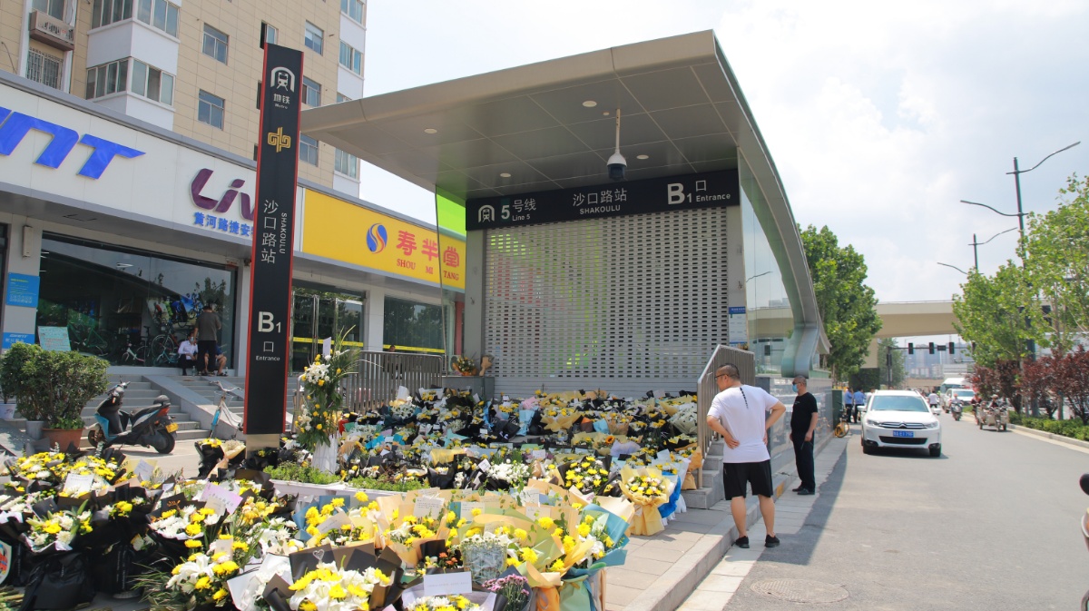 郑州5号线沙口路站地铁口围挡被市民拆除 入口摆满鲜花和卡片祭奠逝者