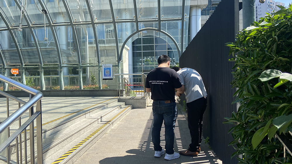 5月22日，地铁6号线世纪大道站外，徐先生和邱先生不停地刷着手机，等待着自己的核酸结果。本文图片  澎湃新闻记者 巩汉语  图