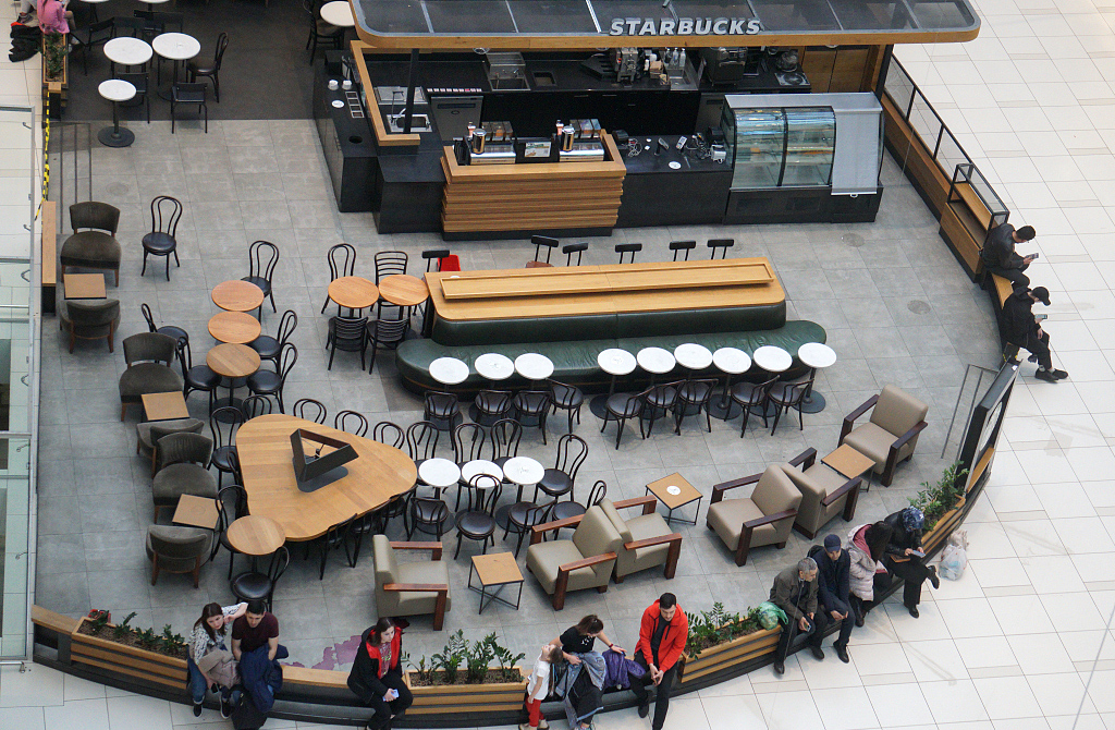 2022年4月24日,俄罗斯莫斯科,人们坐在一家星巴克咖啡店前的长椅上,这家星巴克已经关门。