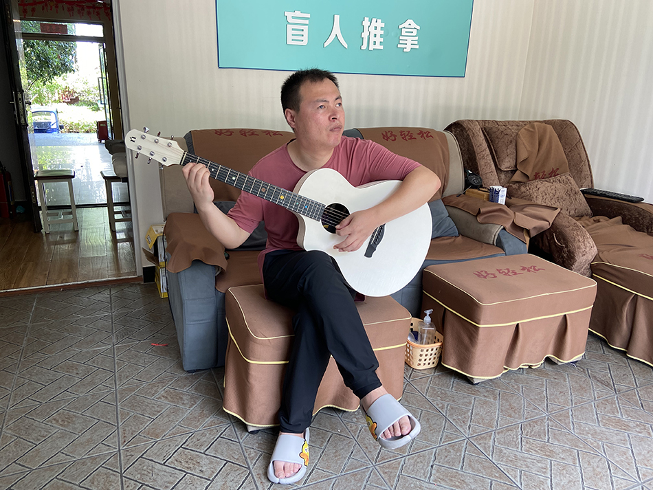 为了打发时间,盲人按摩师任凤来在店里练习吉他。