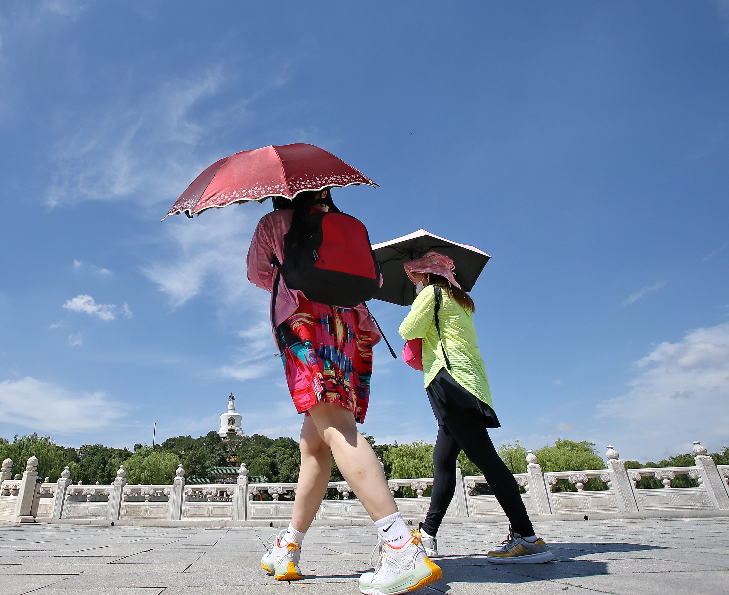 7月6日，北京，“小暑”节气在即，北京回归晴热暴晒模式，午后紫外线照射强烈，“热情”十足。当日在北海公园游客纷纷采取打太阳伞、戴遮阳帽、穿防晒服等各种措施防晒避暑。IC 图