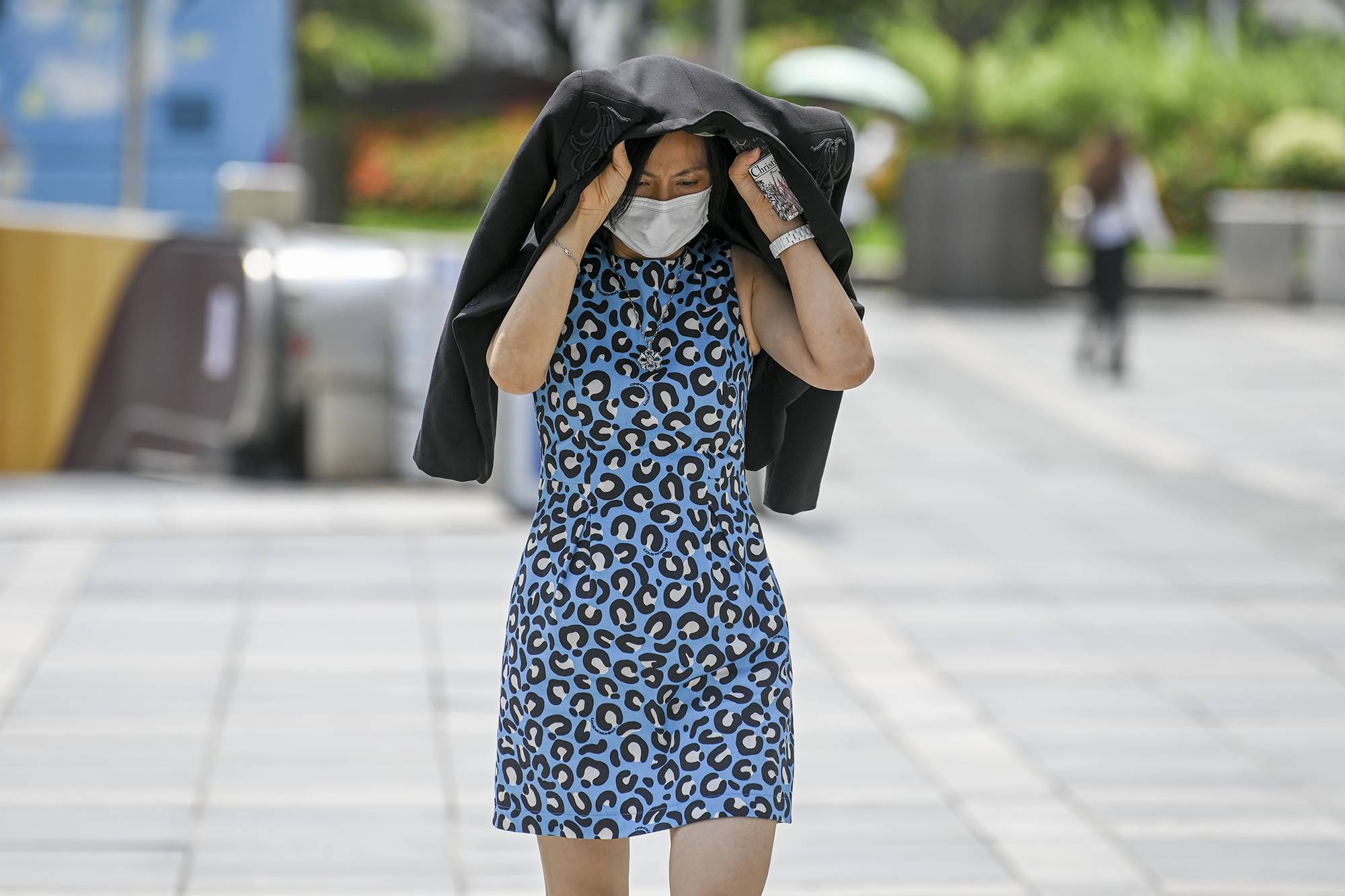 2022年7月11日，上海徐家汇，路人用衣服遮挡阳光出行。澎湃新闻记者朱伟辉图