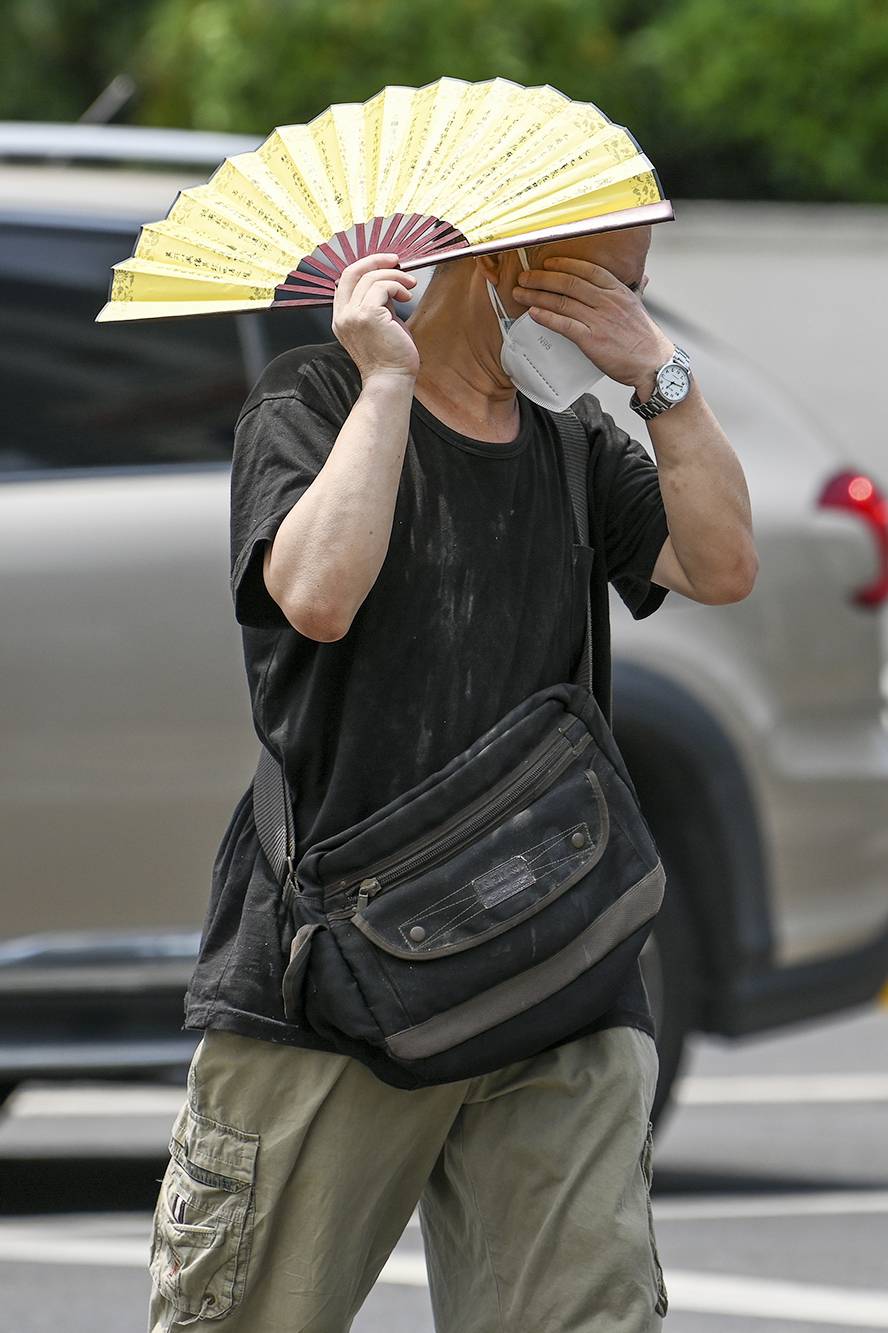 2022年7月11日，上海徐家汇，路人用扇子遮挡阳光出行。澎湃新闻记者朱伟辉图