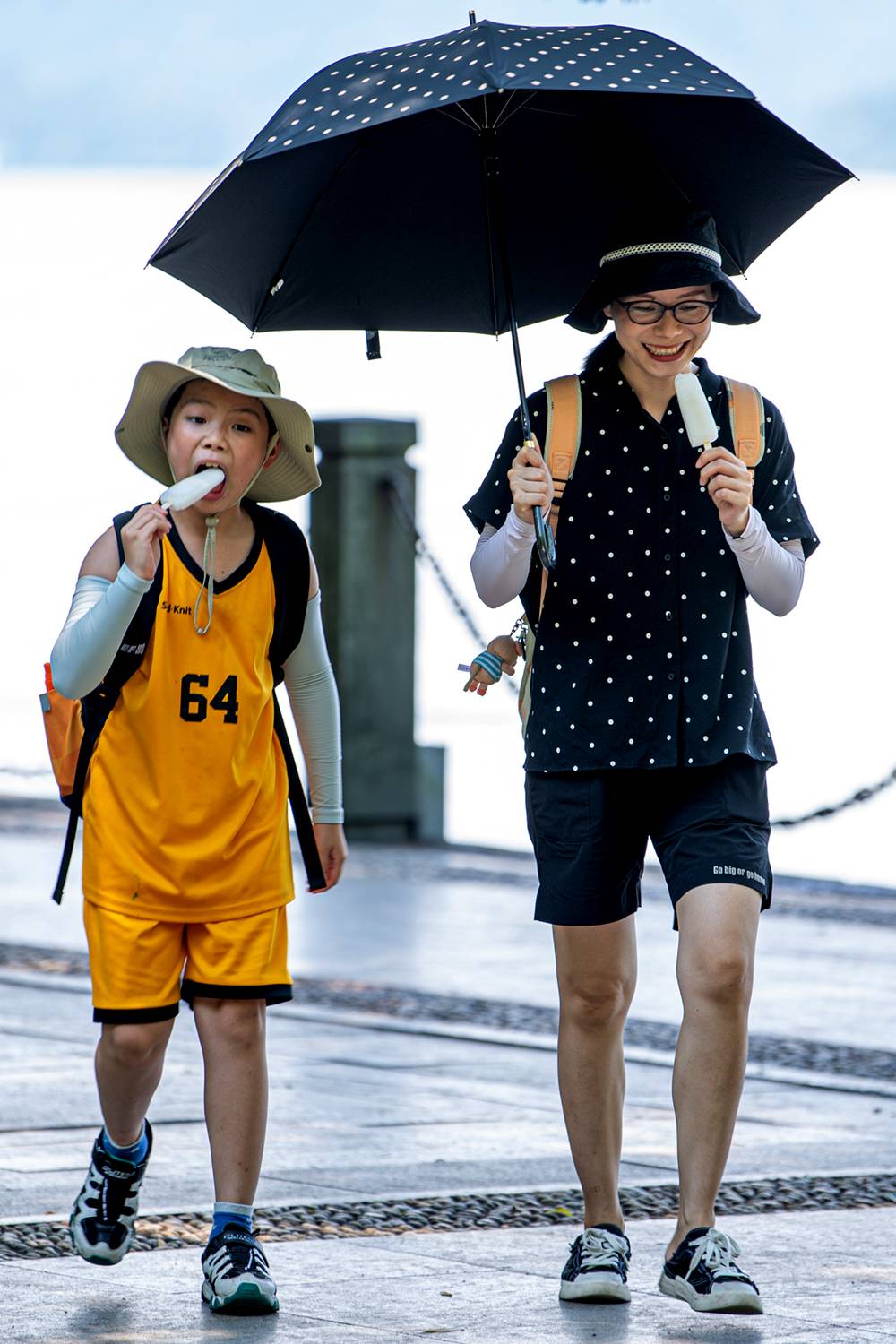 7月14日,游客在西湖畔游览时吃冰棍解暑。