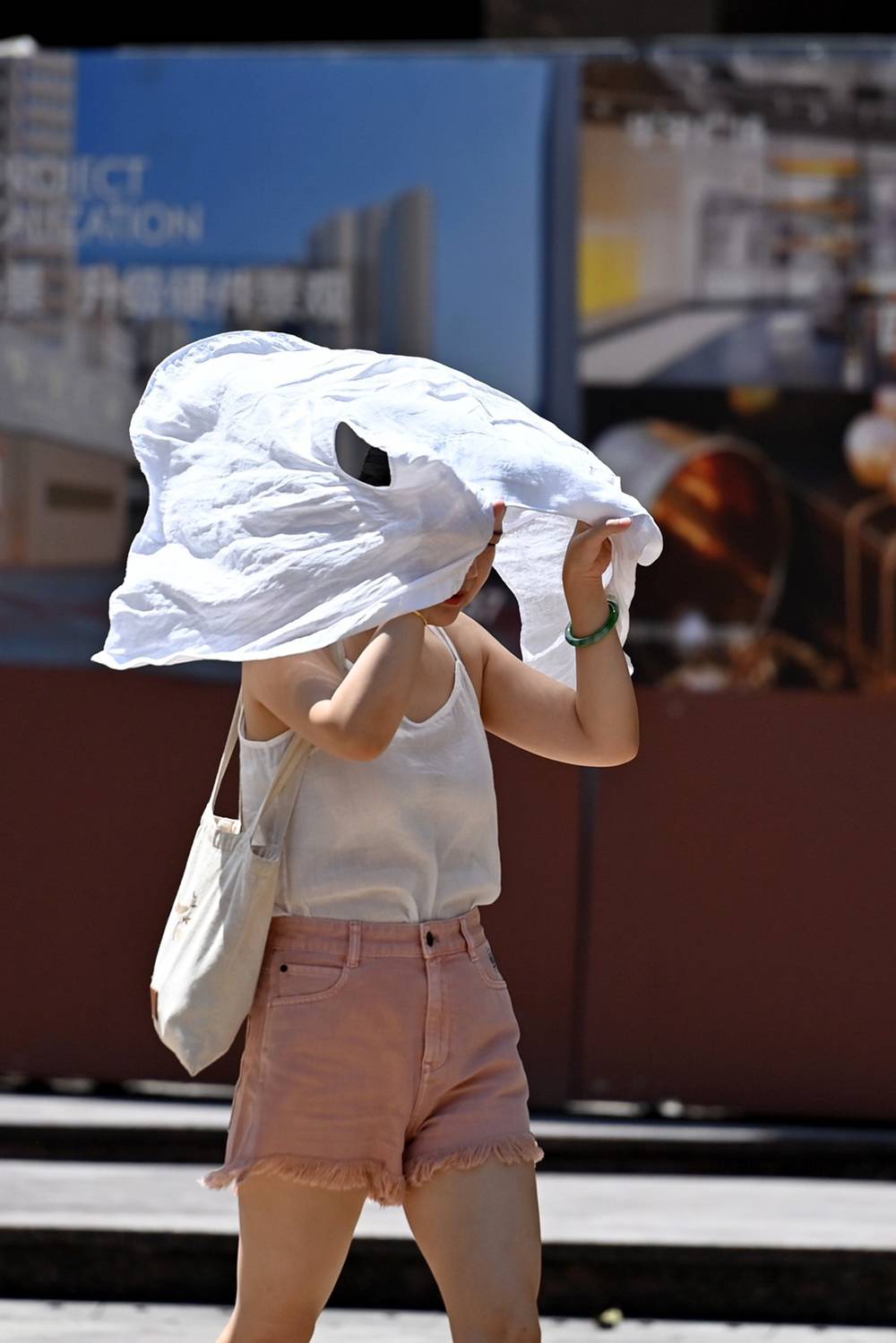 2022年7月14日,重庆市沙坪坝区三峡广场,市民用衬衫遮挡烈日。
