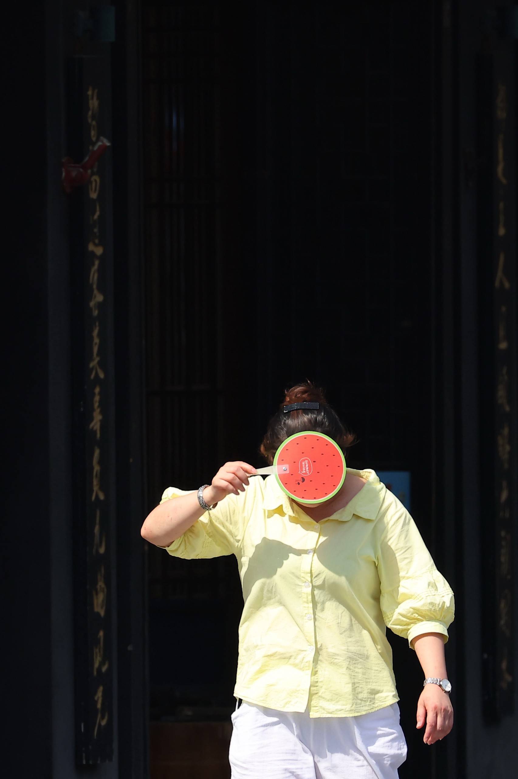 7月12日,江苏南京,市民用一把西瓜小扇遮挡脸部。