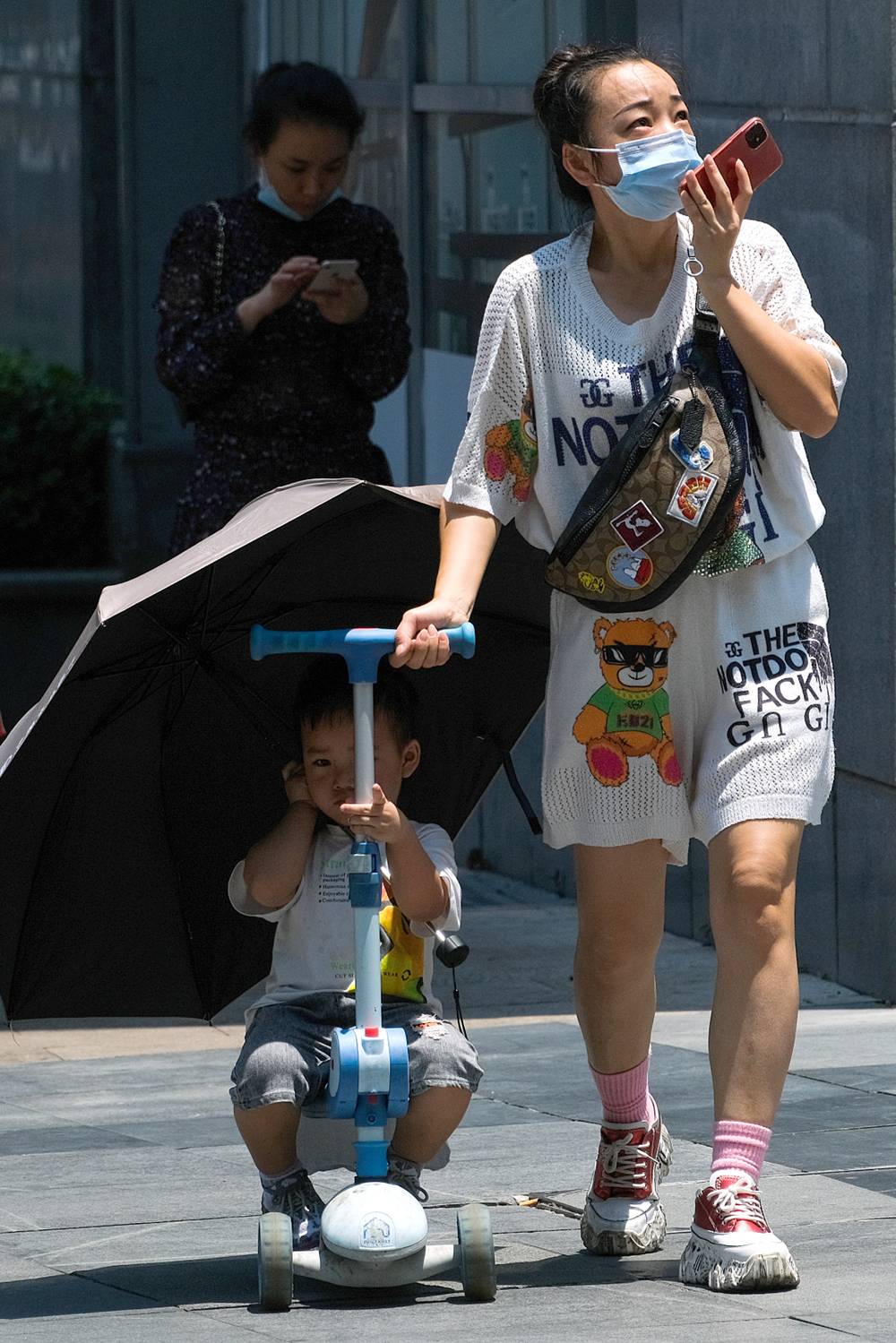 2022年7月14日,重庆,妈妈用伞为儿子遮阳。