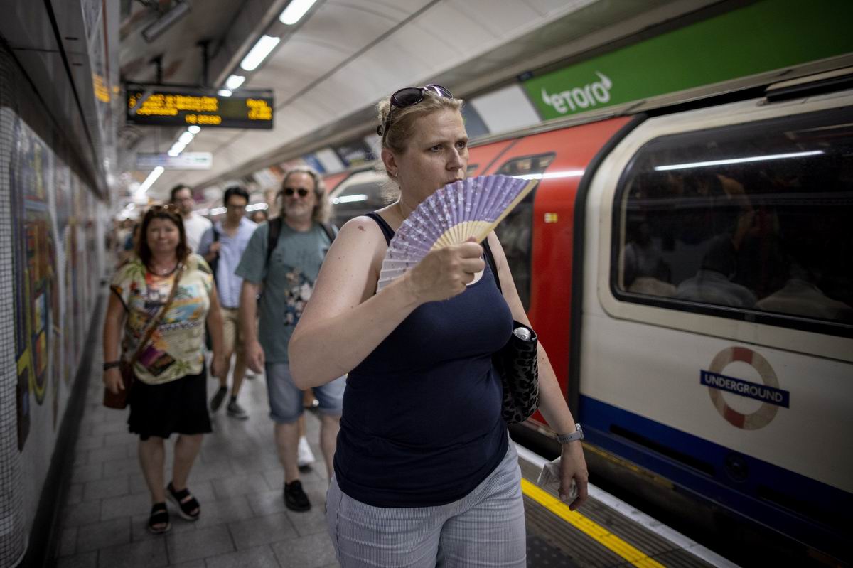 当地时间2022年7月19日,英国伦敦,天气炎热,一名乘客用小扇子降温。
