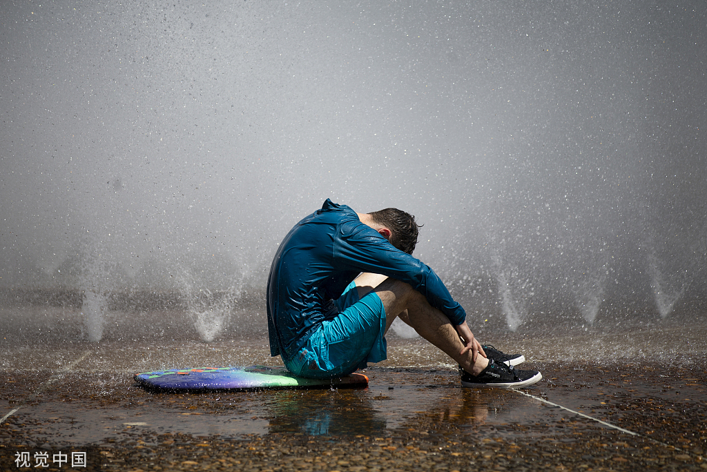 当地时间2022年7月26日，美国俄勒冈州波特兰市，一名男子坐在市中心的Salmon Street Springs喷泉旁。视觉中国 图