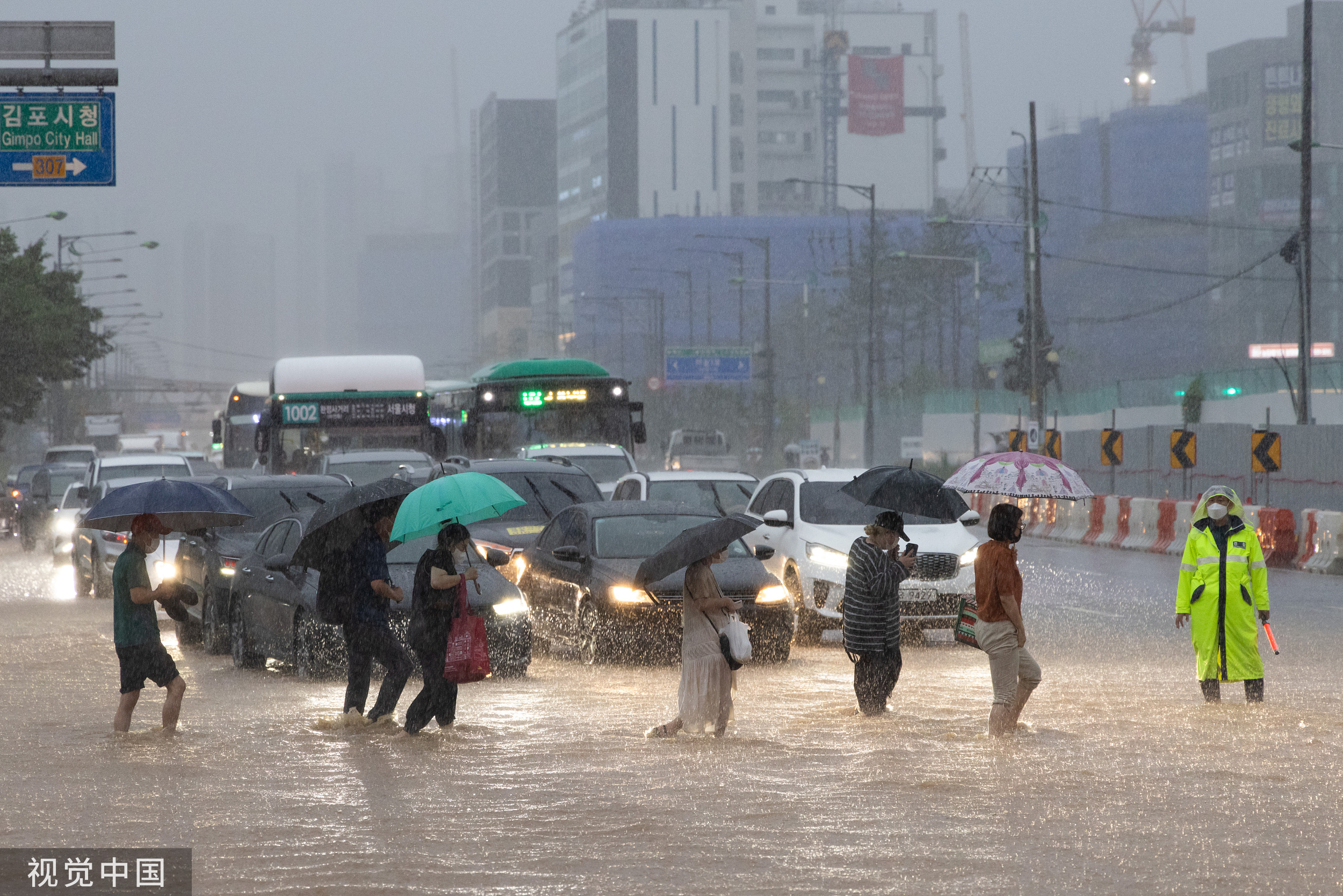 地时间2022年8月9日，韩国金浦，行人穿过被洪水淹没的道路。视觉中国 图