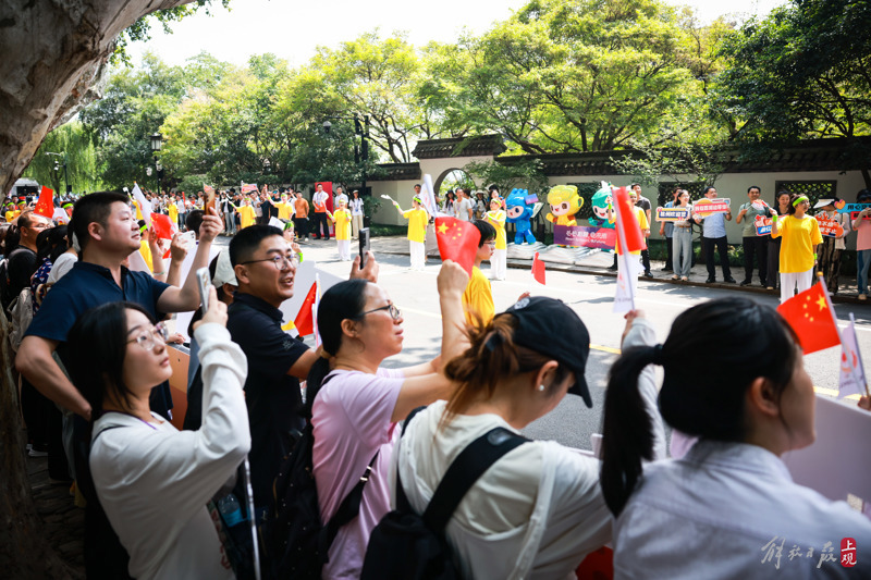 杭州市民在西湖边观摩亚运火炬传递。